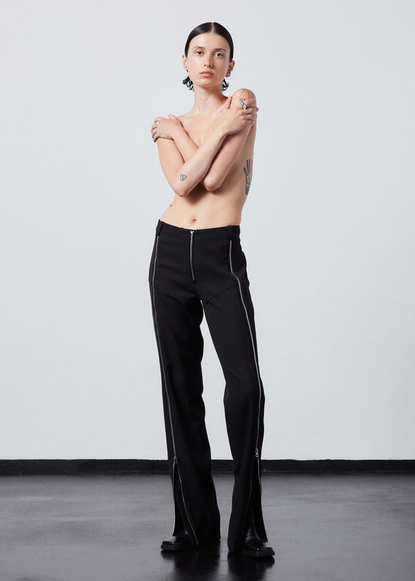 INTERNATIONAL CITIZEN.  Style: The Racer Pants have zippers down the entire front legs from the waistband to the hemline and a fly front zip. Made of Italian Wool RWS, Obsidian Black. Spiritually Infused, Sustainable Luxury Fashion in Berlin. Full front photo.