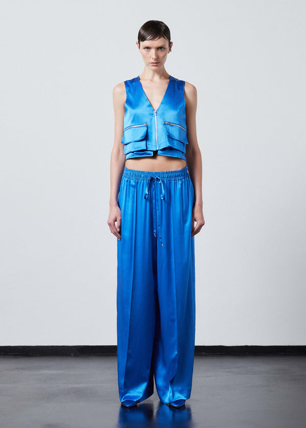 INTERNATIONAL CITIZEN.  Style: The Arcana Pant. Full body front view has a relaxed fit with front pin-tucks and excessive volume eased into the waistband. Unisex Item. The pants are made of Italian organic silk in Azurite Blue. Spiritually Infused, Sustainable Luxury Fashion in Berlin.