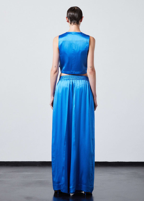 INTERNATIONAL CITIZEN.  Style: The Arcana Pant. Full body back view. Style has a relaxed fit with front pin-tucks and excessive volume eased into the waistband. Unisex Item. The pants are made of Italian organic silk in Azurite Blue. Spiritually Infused, Sustainable Luxury Fashion in Berlin.