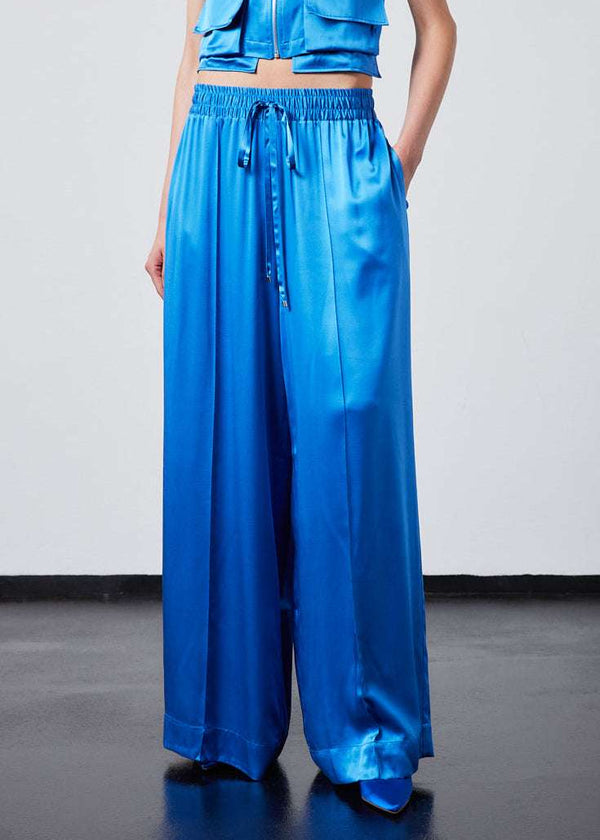 INTERNATIONAL CITIZEN.  Style: The Arcana Pant. Front close up. Style has a relaxed fit with front pin-tucks and excessive volume eased into the waistband. Unisex Item. The pants are made of Italian organic silk in Azurite Blue. Spiritually Infused, Sustainable Luxury Fashion in Berlin.
