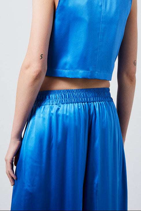 INTERNATIONAL CITIZEN.  Style: The Arcana Pant. Close up back view. Style has a relaxed fit with front pin-tucks and excessive volume eased into the waistband. Unisex Item. The pants are made of Italian organic silk in Azurite Blue. Spiritually Infused, Sustainable Luxury Fashion in Berlin.