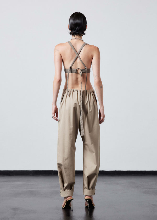 INTERNATIONAL CITIZEN.  Style: The JiuJitsu Pants are have a drawstring closer at the waist, a straight leg with silver snap hem straps and a thigh patch. Unisex item. Full body back photo. Made of Italian Organic Cotton Twill, Dune. Spiritually Infused, Sustainable Luxury Fashion in Berlin.