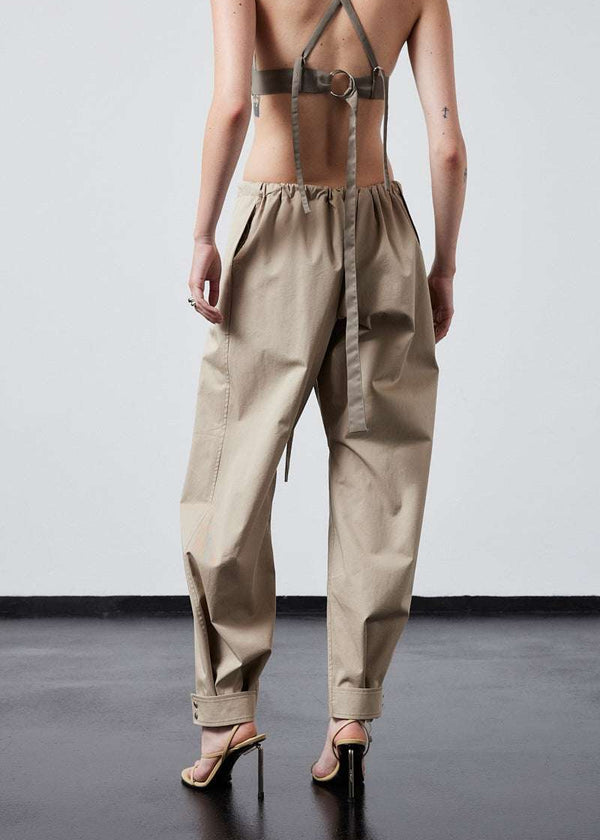 INTERNATIONAL CITIZEN.  Style: The JiuJitsu Pants are have a drawstring closer at the waist, a straight leg with silver snap hem straps. Unisex item. Cropped back photo. Made of Italian Organic Cotton Twill, Dune. Spiritually Infused, Sustainable Luxury Fashion in Berlin.