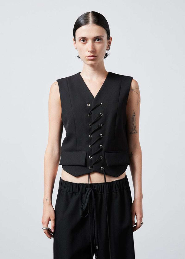 INTERNATIONAL CITIZEN.  Style: The Stitch Vest features a high neckline with overlapping front closure held with an eyelet stitch lacing detail. Made of Italian Wool RWS, Obsidian Black. Spiritually Infused, Sustainable Luxury Fashion in Berlin. Front body photo.