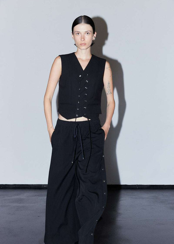INTERNATIONAL CITIZEN.  Style: The Stitch Vest. Made of Italian Wool RWS, Obsidian Black. Spiritually Infused, Sustainable Luxury Fashion in Berlin. Walking front photo. 