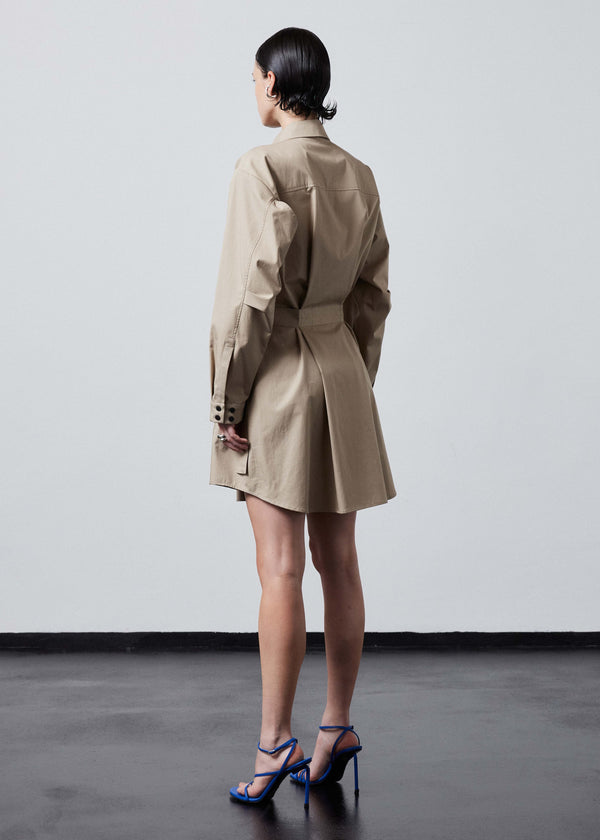 INTERNATIONAL CITIZEN.  Style: Artist Shirt Dress. Side back view. Style has an oversized shirt with a pen pocket at the chest, open underarms for breathability, and back belt ties that adjust at the front with silver rings. The shirt are made of Italian organic Cotton Twill in Dune. Spiritually Infused, Sustainable Luxury Fashion in Berlin.