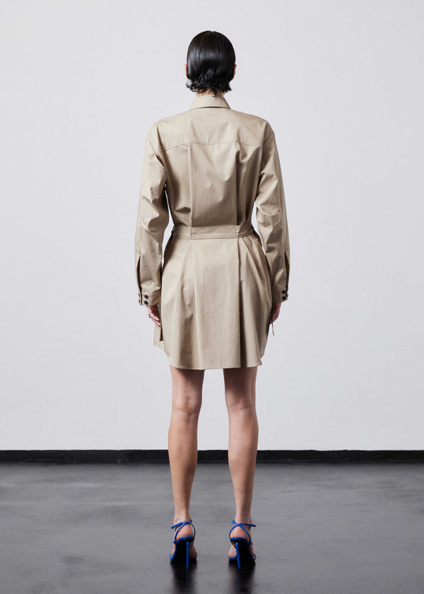INTERNATIONAL CITIZEN.  Style: Artist Shirt Dress. Back full body view. Style has an oversized shirt with a pen pocket at the chest, open underarms for breathability, and back belt ties that adjust at the front with silver rings. The shirt are made of Italian organic Cotton Twill in Dune. Spiritually Infused, Sustainable Luxury Fashion in Berlin.