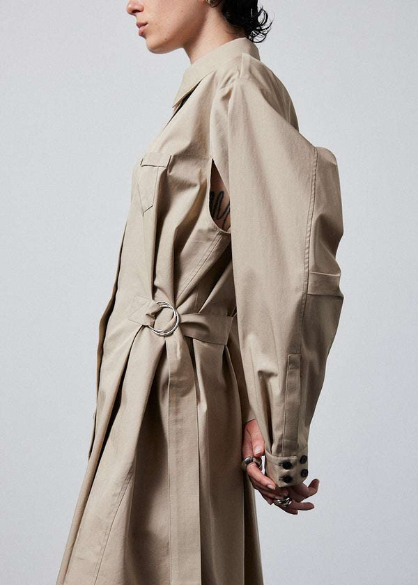 INTERNATIONAL CITIZEN.  Style: Artist Shirt Dress. Side close up view. Style has an oversized shirt with a pen pocket at the chest, open underarms for breathability, and back belt ties that adjust at the front with silver rings. The shirt are made of Italian organic Cotton Twill in Dune. Spiritually Infused, Sustainable Luxury Fashion in Berlin.