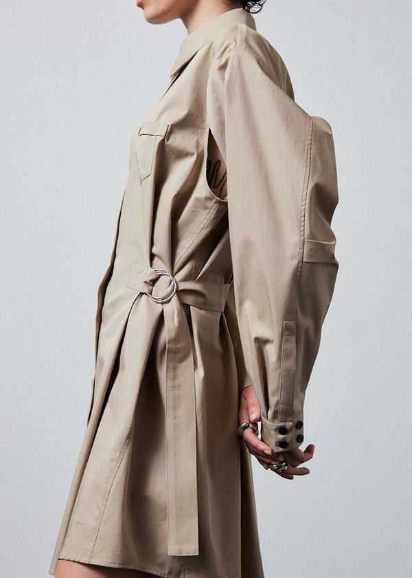 INTERNATIONAL CITIZEN.  Style: Artist Shirt Dress. Side view. Style has an oversized shirt with a pen pocket at the chest, open underarms for breathability, and back belt ties that adjust at the front with silver rings. The shirt are made of Italian organic Cotton Twill in Dune. Spiritually Infused, Sustainable Luxury Fashion in Berlin.