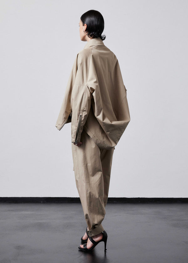 INTERNATIONAL CITIZEN.  Style: The Cube Coat, is a 3D cube tilted on its axes to create a boxy minimal front body and dramatic drape in the back body. Unisex style. Side back view. Made of Italian Organic Cotton Twill, Dune. Spiritually Infused, Sustainable Luxury Fashion in Berlin.