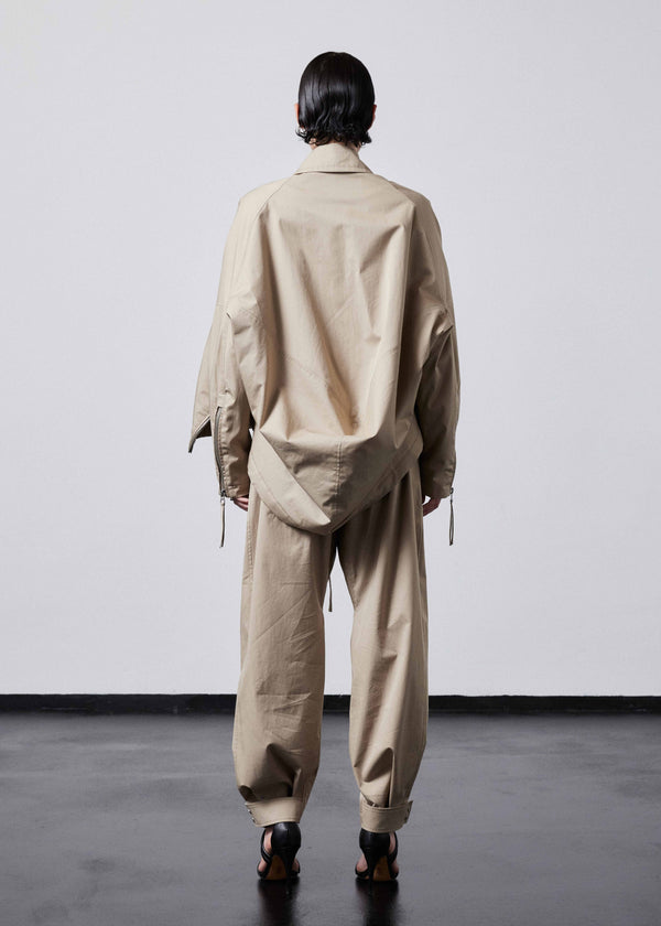 INTERNATIONAL CITIZEN.  Style: The Cube Coat, is a 3D cube tilted on its axes to create a dramatic drape in the back body. Unisex style. Back view. Made of Italian Organic Cotton Twill, Dune. Spiritually Infused, Sustainable Luxury Fashion in Berlin.