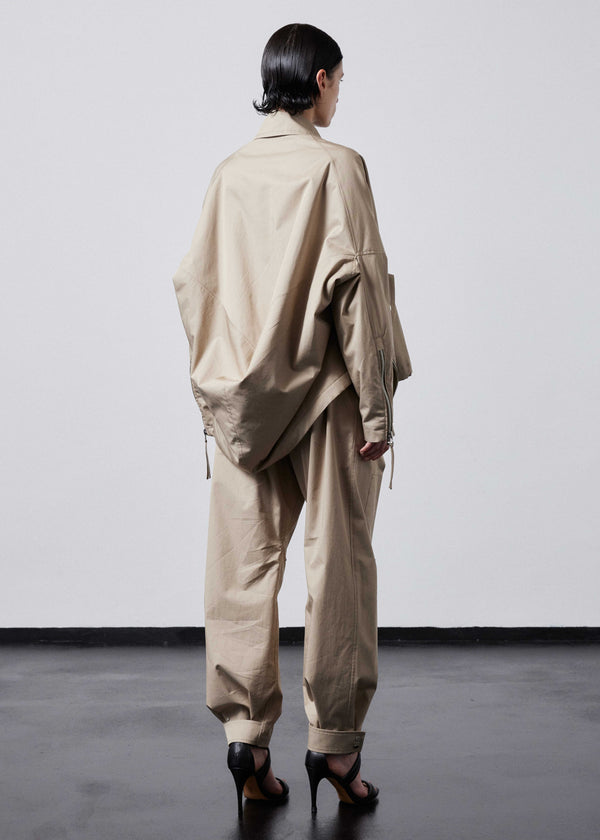 INTERNATIONAL CITIZEN.  Style: The Cube Coat, is a 3D cube tilted on its axes to create a boxy minimal front body and dramatic drape in the back body. Right side back view  Unisex style. Made of Italian Organic Cotton Twill, Dune. Spiritually Infused, Sustainable Luxury Fashion in Berlin.