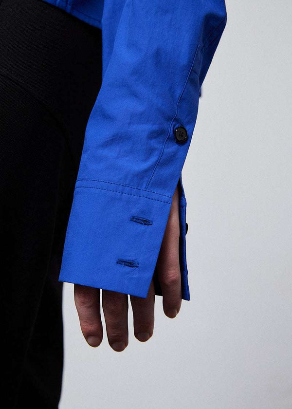 INTERNATIONAL CITIZEN.  Style: The Stitch Shirt transforms into multiple iterations. Made of Italian Organic Cotton, Lapis Lazuli Blue. Spiritually Infused, Sustainable Luxury Fashion in Berlin. Close up of front sleeve.