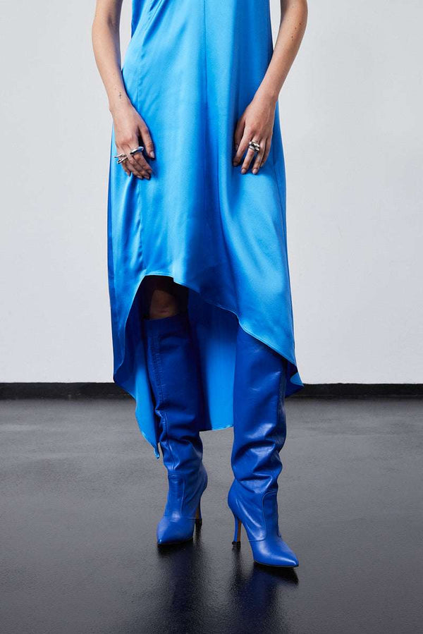INTERNATIONAL CITIZEN.  Style: The Crystalline Dress. Back view of model in blue satin dress with uneven hemline. Made of Organic Silk, Azurite Blue. Spiritually Infused, Sustainable Luxury Fashion in Berlin.