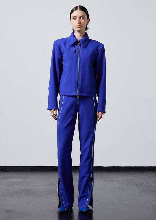INTERNATIONAL CITIZEN.  Style: Ajna Jacket - a blue boxy jacket with sporty tailoring, featuring square shoulders, tapered sleeves, and zipper closures. The jacket is made from of Italian Wool in Lapis Lazuli Blue. Model is wearing it with matching pants. Spiritually Infused, Sustainable Luxury Fashion in Berlin.