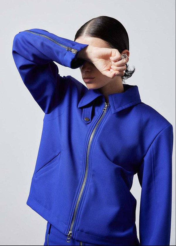 INTERNATIONAL CITIZEN.  Style: Ajna Jacket - a blue boxy jacket with sporty tailoring, featuring square shoulders, tapered sleeves, and zipper closures. Close up photo of the sleeves. The jacket is made from of Italian Wool in Lapis Lazuli Blue. Spiritually Infused, Sustainable Luxury Fashion in Berlin.
