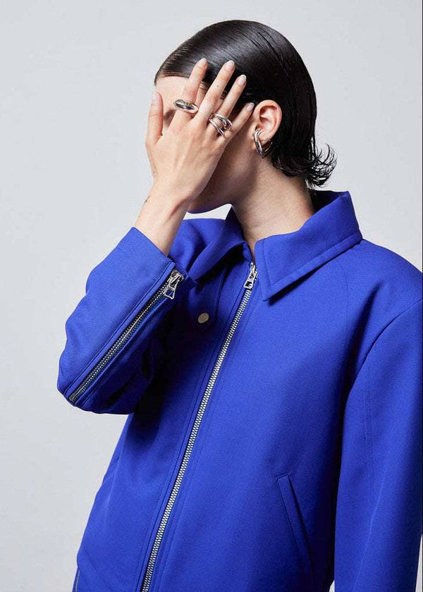 INTERNATIONAL CITIZEN.  Style: Ajna Jacket - side view a blue boxy jacket with sporty tailoring, featuring zipper closures. The jacket is made from of Italian Wool in Lapis Lazuli Blue. Spiritually Infused, Sustainable Luxury Fashion in Berlin.