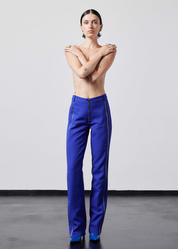 INTERNATIONAL CITIZEN.  Style: The Racer Pants have zippers down the entire front legs from the waistband to the hemline and a fly front zip. Made of Italian Wool RWS, Lapis Lazuli Blue. Spiritually Infused, Sustainable Luxury Fashion in Berlin. Full body front photo.