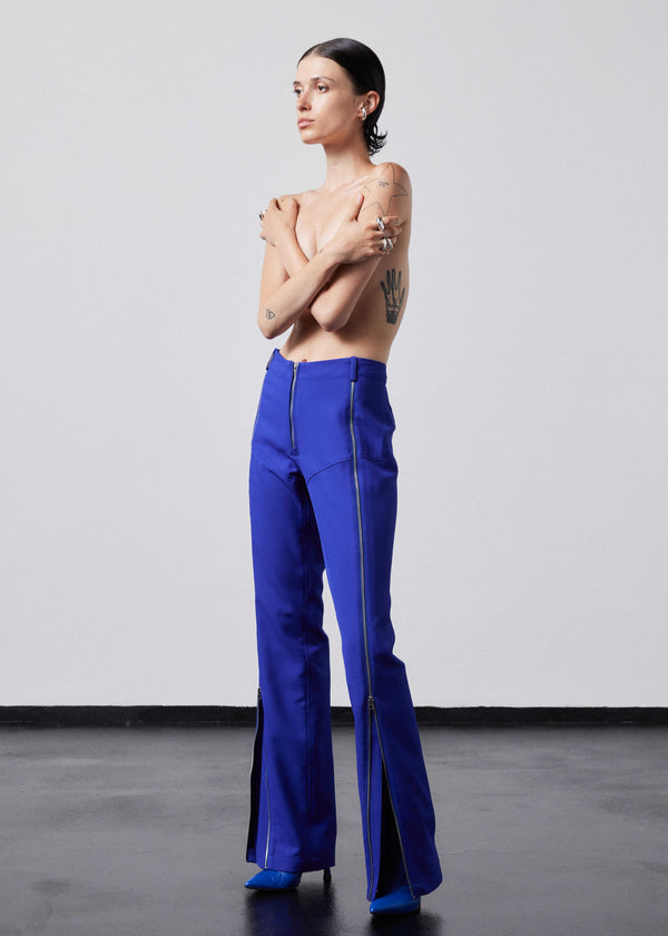 INTERNATIONAL CITIZEN.  Style: The Racer Pants have zippers down the entire front legs from the waistband to the hemline and a fly front zip. Made of Italian Wool RWS, Lapis Lazuli Blue. Spiritually Infused, Sustainable Luxury Fashion in Berlin. Full body side front photo.