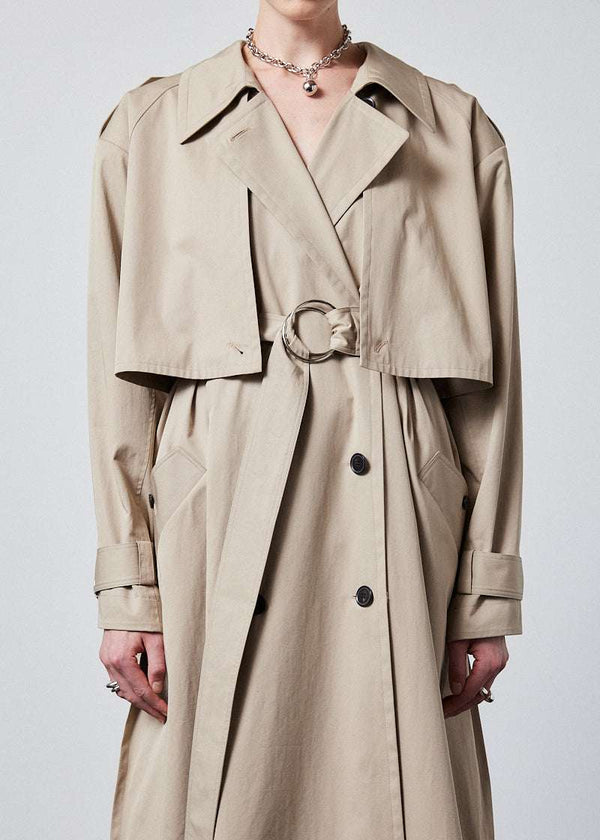 INTERNATIONAL CITIZEN.  Style: The Equinox Trench Coat, is voluminous and features classic trench coat detailing. Unisex item. Close up front view.  Made of Italian Organic Cotton, Dune. Spiritually Infused, Sustainable Luxury Fashion in Berlin.