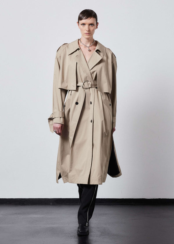 INTERNATIONAL CITIZEN.  Style: The Equinox Trench Coat, is voluminous and it features classic trench coat detailing, & removable shoulder pads. Unisex item.  Full front view. Made of Italian Organic Cotton, Dune. Spiritually Infused, Sustainable Luxury Fashion in Berlin.