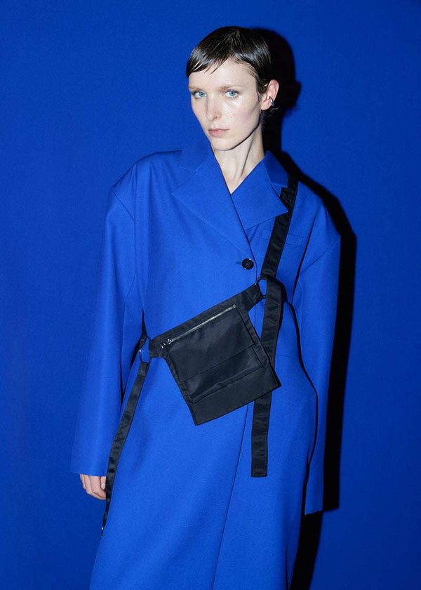 INTERNATIONAL CITIZEN.  Style: The M24 Cross Body Bag features a zipper welt pocket and patch pocket flap with adjustable ring straps. Unisex Item. Made of Italian post-consumer recycled Nylon, Obsidian Black. Spiritually Infused, Sustainable Luxury Fashion in Berlin. Worn on a model.