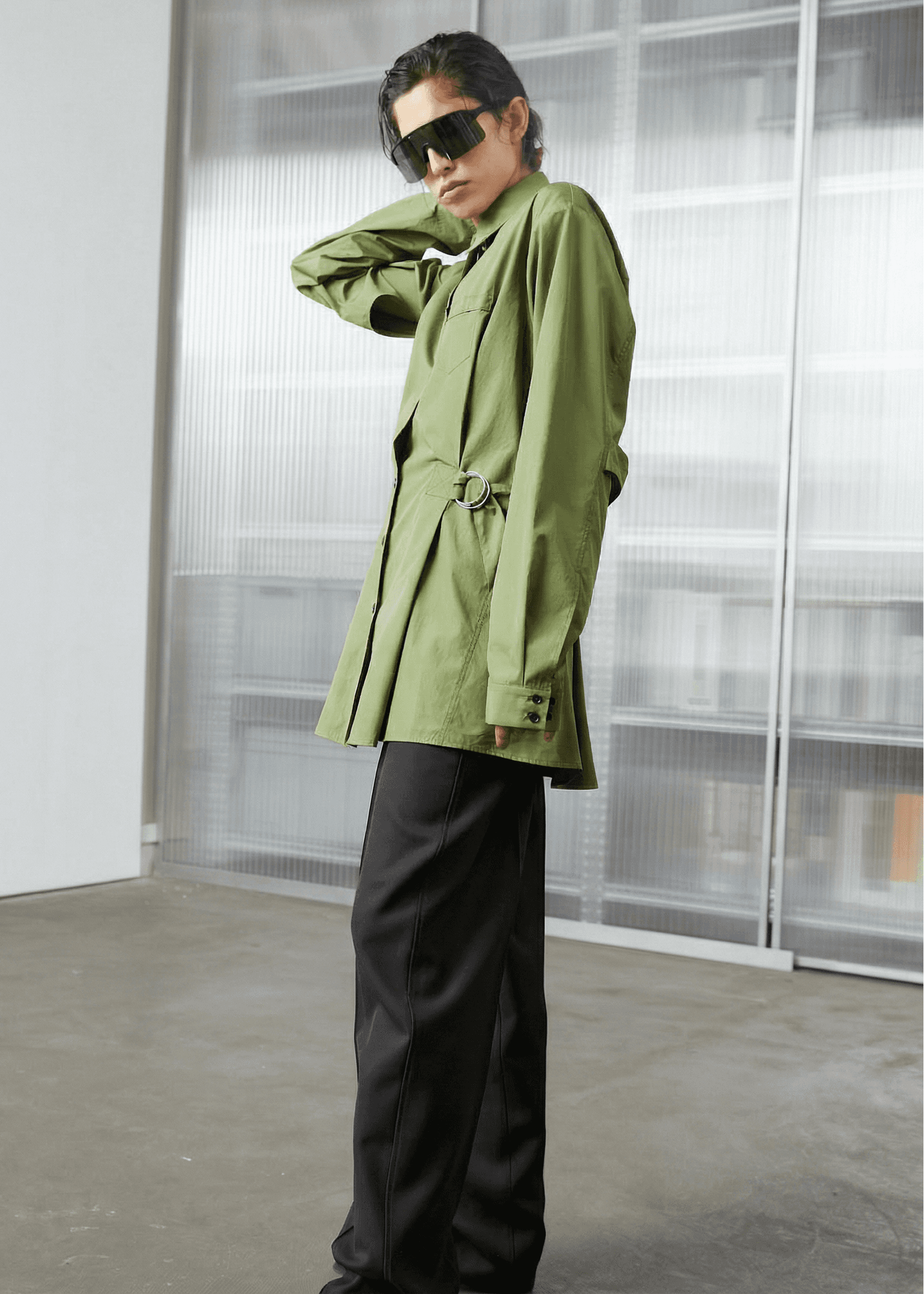 INTERNATIONAL CITIZEN.  Style: Artist Shirt Dress. Side front view. The style has an oversized shirt with a pen pocket at the chest, open underarms for breathability, and back belt ties that adjust at the front with silver rings. The shirt are made of Italian organic Cotton Twill in Nephrite Jade. Spiritually Infused, Sustainable Luxury Fashion in Berlin.
