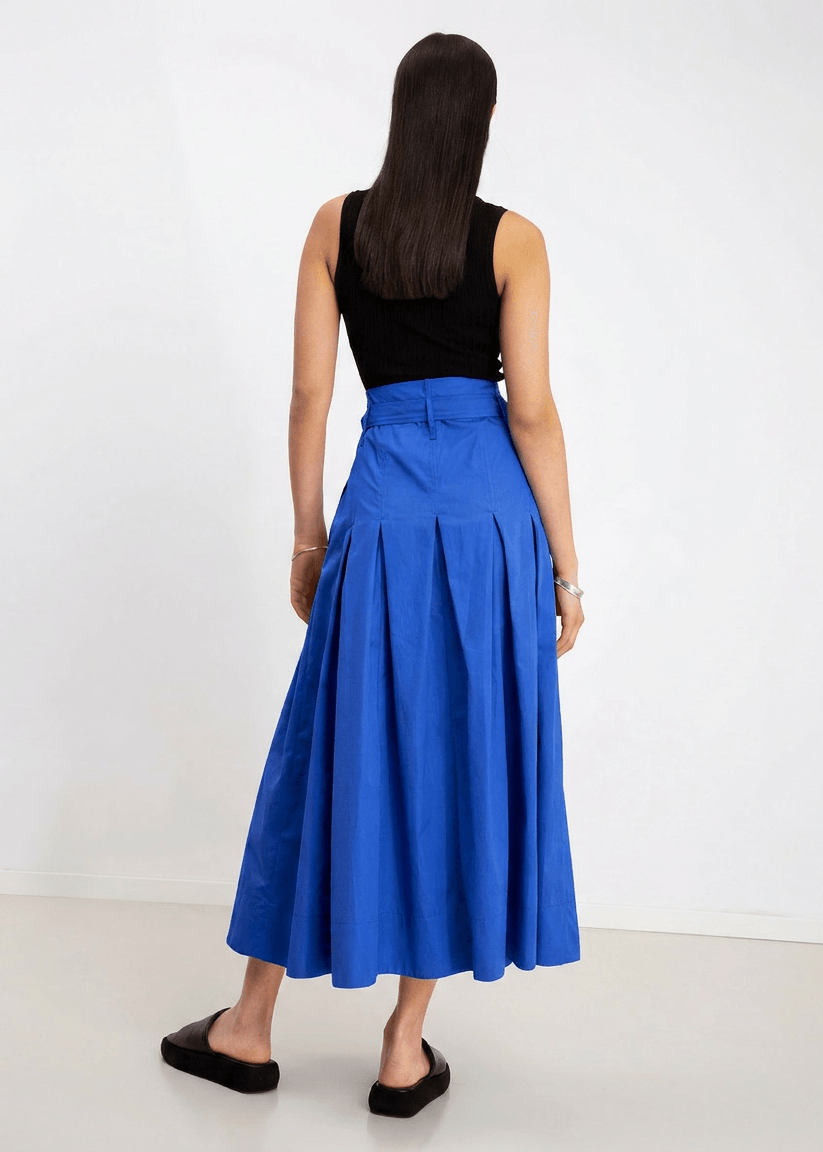 INTERNATIONAL CITIZEN.  Style: Button Skirt. A Button Skirt with box pleats below the hips. Back full view. The skirt is made of Italian organic Cotton in Lapis Lazuli. Spiritually Infused, Sustainable Luxury Fashion in Berlin.