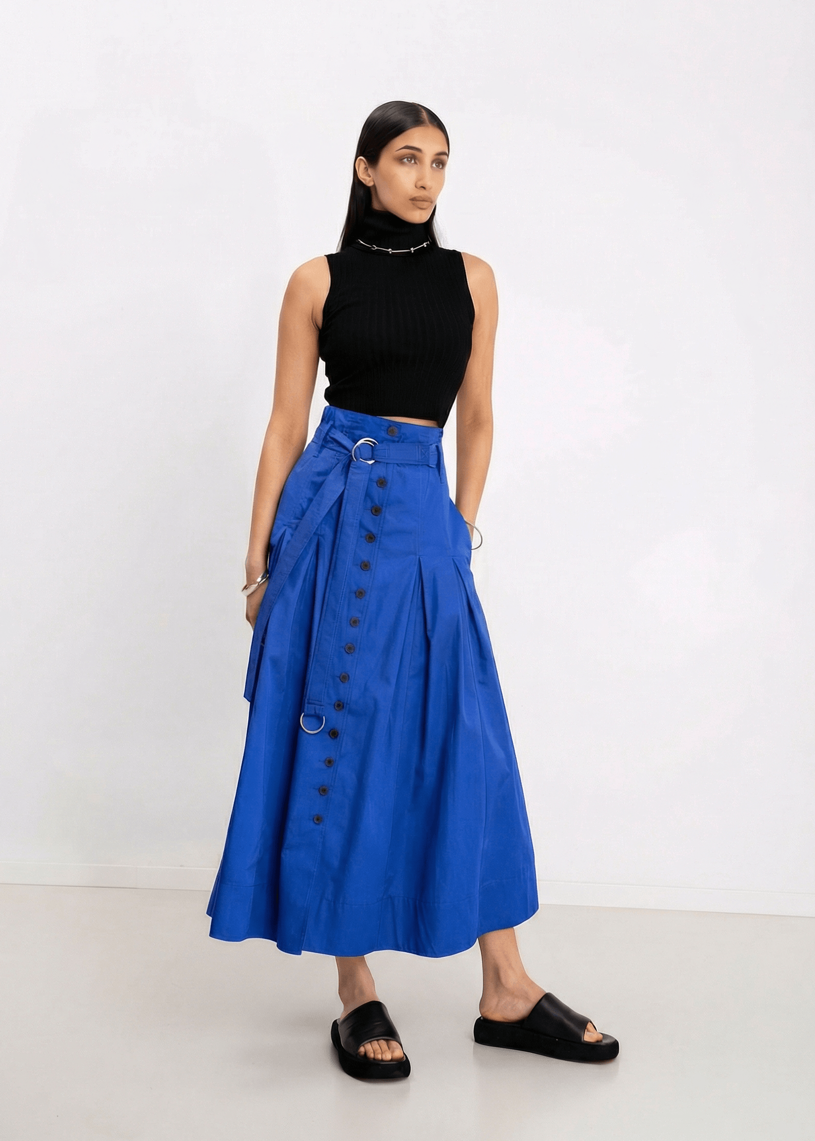 INTERNATIONAL CITIZEN.  Style: Button Skirt. A Button Skirt with box pleats below the hips. Front full view. The skirt is made of Italian organic Cotton in Lapis Lazuli. Spiritually Infused, Sustainable Luxury Fashion in Berlin.