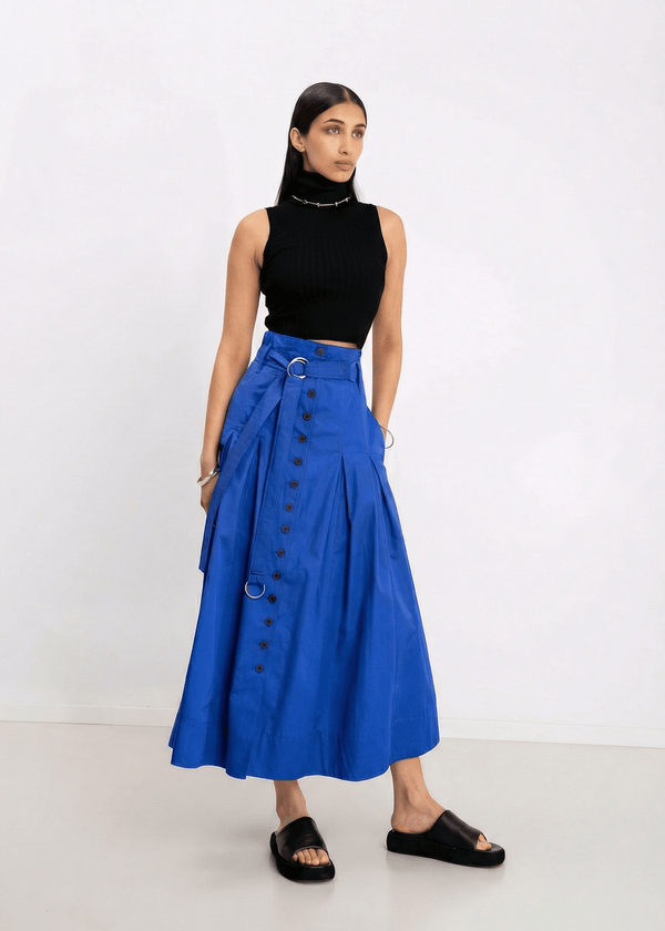 INTERNATIONAL CITIZEN.  Style: Button Skirt. A Button Skirt with box pleats below the hips. Front full view. The skirt is made of Italian organic Cotton in Lapis Lazuli. Spiritually Infused, Sustainable Luxury Fashion in Berlin.