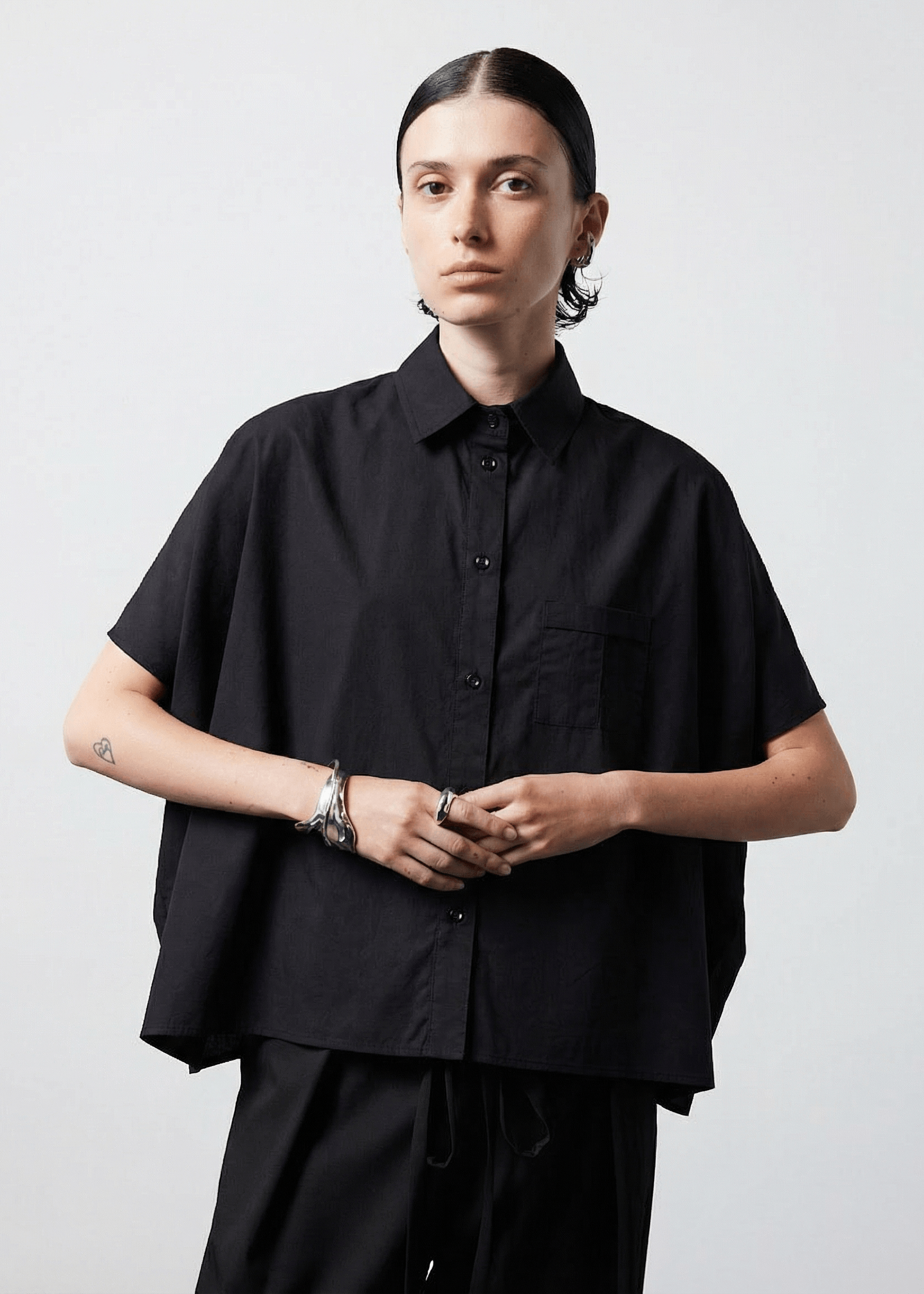 INTERNATIONAL CITIZEN.  Style: The Cubism Shirt is a 3-dimensional cube tilted on its axes to create a boxy minimal front body and dramatic drape in the back body and a utility pen pocket on the chest. Unisex Item. Made of Italian Organic Cotton, Obsidian Black. Spiritually Infused, Sustainable Luxury Fashion in Berlin.