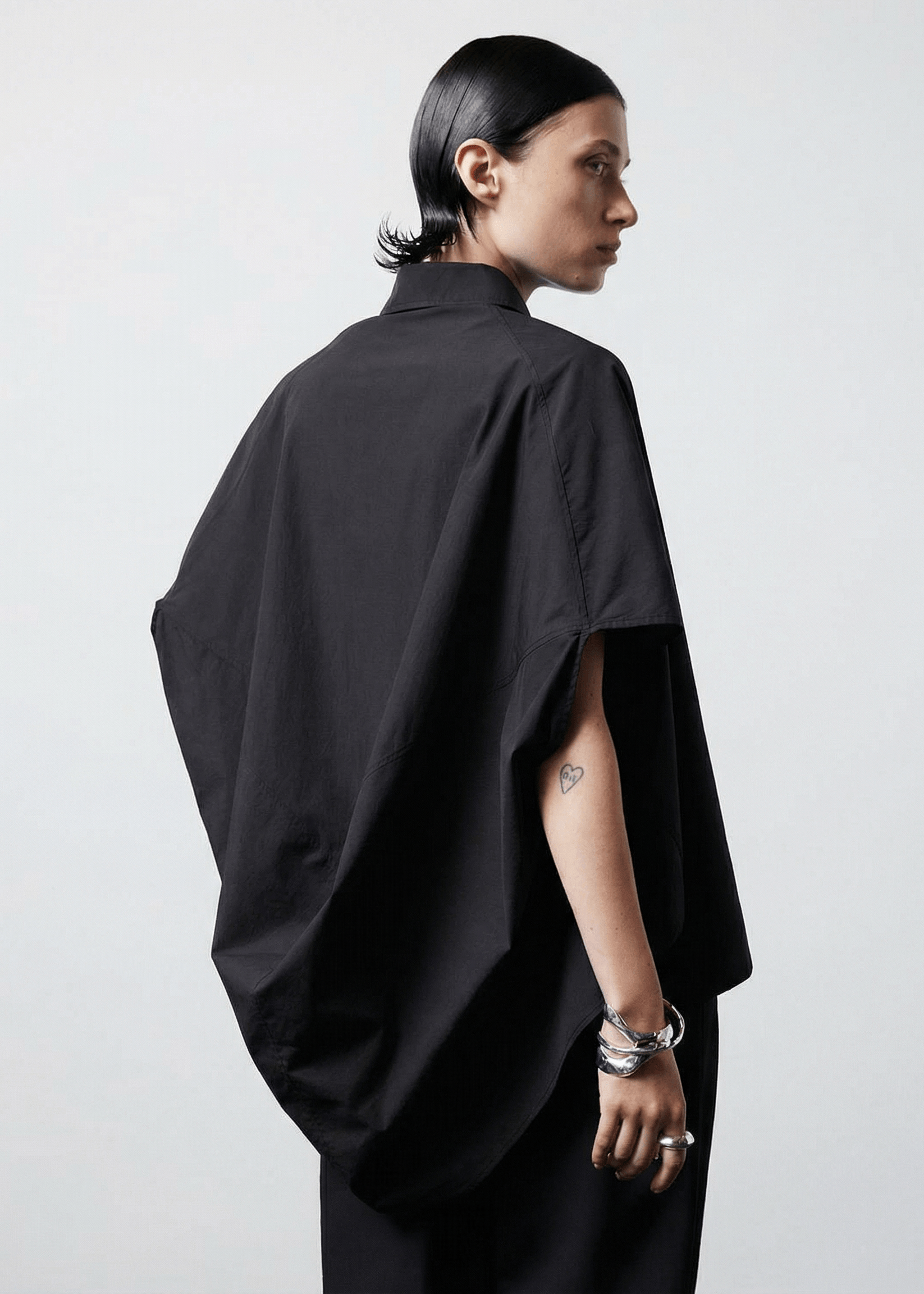 INTERNATIONAL CITIZEN.  Style: The Cubism Shirt is a 3-dimensional cube tilted on its axes to create a boxy minimal  body and dramatic drape in the back body. Back view. Unisex Item. Made of Italian Organic Cotton, Obsidian Black. Spiritually Infused, Sustainable Luxury Fashion in Berlin.