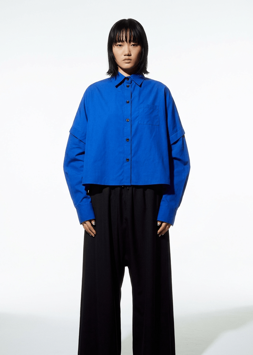 INTERNATIONAL CITIZEN.  Style: The Cubism Shirt is a 3-dimensional cube tilted on its axes to create a boxy minimal front body  and a utility pen pocket on the chest. Unisex Item. Made of Italian Organic Cotton, Lapis Lazuli Blue. Spiritually Infused, Sustainable Luxury Fashion in Berlin.