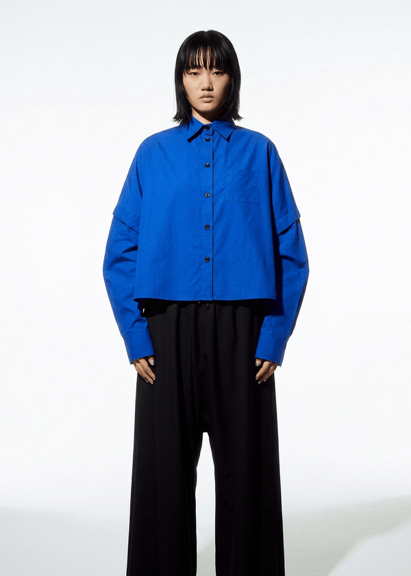 INTERNATIONAL CITIZEN.  Style: The Cubism Shirt is a 3-dimensional cube tilted on its axes to create a boxy minimal front body  and a utility pen pocket on the chest. Unisex Item. Made of Italian Organic Cotton, Lapis Lazuli Blue. Spiritually Infused, Sustainable Luxury Fashion in Berlin.