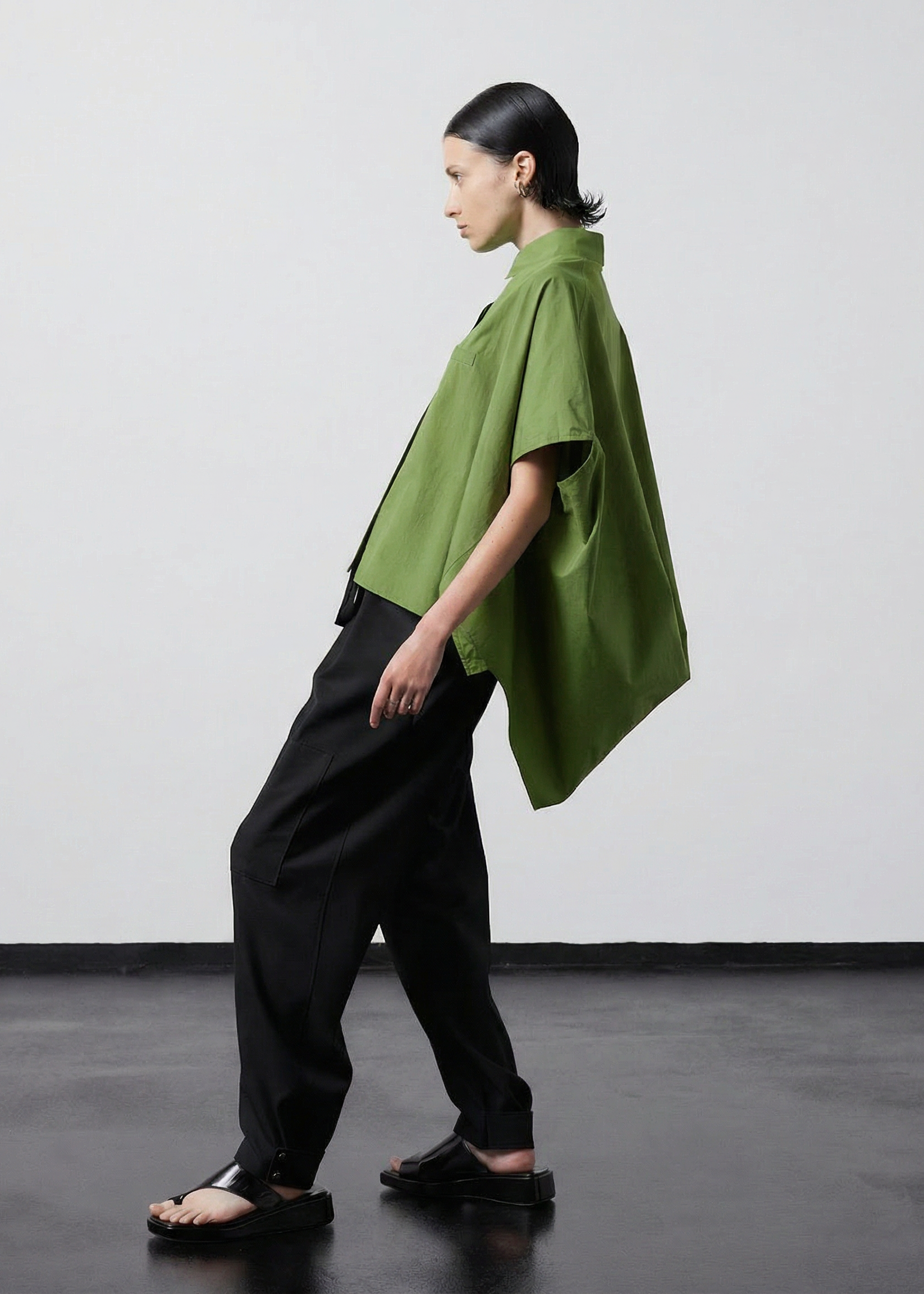 INTERNATIONAL CITIZEN.  Style: The Cubism Shirt is a 3-dimensional cube tilted on its axes to create a boxy minimal front body and dramatic drape in the back body. Full body side view. Unisex Item. Made of Italian Organic Cotton,Nephrite Jade Green. Spiritually Infused, Sustainable Luxury Fashion in Berlin.