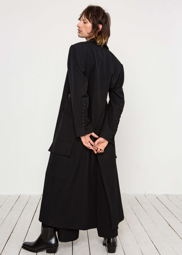 INTERNATIONAL CITIZEN.  Style: Duster Coat. A unisex coat that features traditional men's tailoring construction details. Side back view. The coat is made of Italian RWS Wool in Obsidian Black. Spiritually Infused, Sustainable Luxury Fashion in Berlin.
