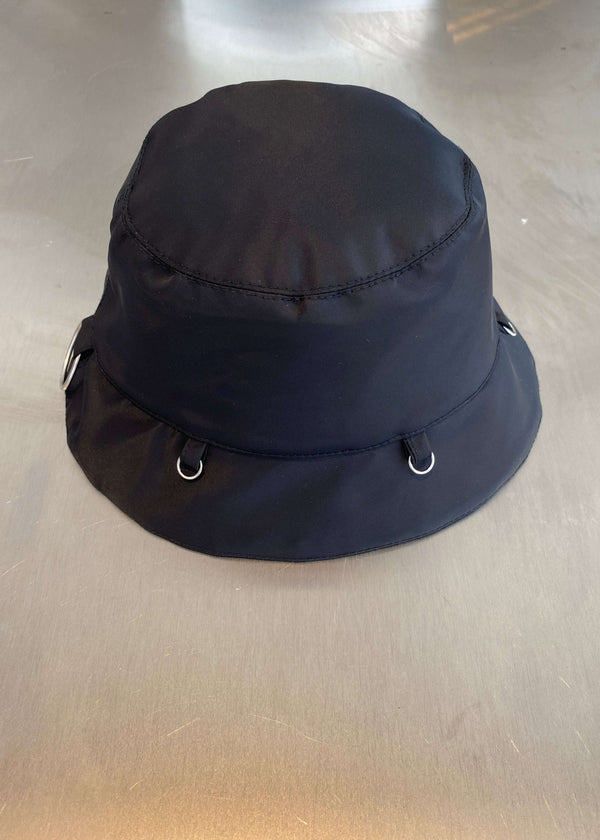 INTERNATIONAL CITIZEN.  Style: The Charm Bucket Hat. Side view. A unisex hat with utility details that feature our signature silver ring at the back and mini rings around the rim to clip your charms. Made of Italian post-consumer recycled Nylon, Obsidian Black. Spiritually Infused, Sustainable Luxury Fashion in Berlin.
