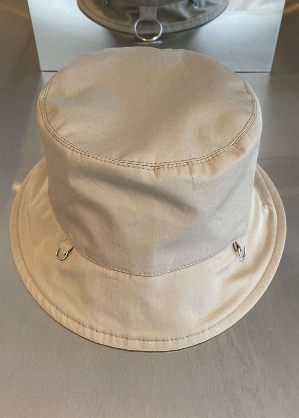 INTERNATIONAL CITIZEN.  Style: The Charm Bucket Hat. Front view. A unisex hat with utility details that feature our signature silver ring at the back and mini rings around the rim to clip your charms.  Made of Italian Organic Cotton Twill, Dune. Spiritually Infused, Sustainable Luxury Fashion in Berlin.
