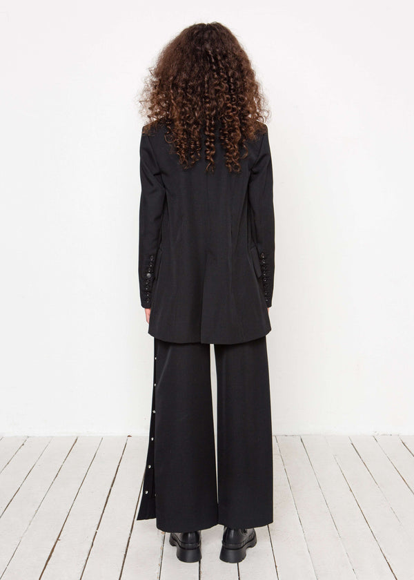 INTERNATIONAL CITIZEN.  Style: The Heart Opener Jacket features slim sleeves cut on the bias, a clean fitted shoulder and straight body, creating a cool silhouette. Full body back view.  Made of Italian Wool, certified (RWS) Responsible Wool Standard, Obsidian Black. Spiritually Infused, Sustainable Luxury Fashion in Berlin.