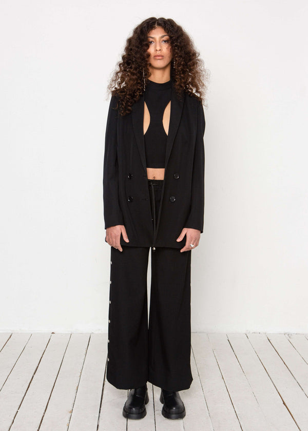 INTERNATIONAL CITIZEN.  Style: The Heart Opener Jacket features slim sleeves cut on the bias, a clean fitted shoulder and straight body, creating a cool silhouette that can be belted for an hourglass shape. Made of Italian Wool, certified (RWS) Responsible Wool Standard, Obsidian Black. Spiritually Infused, Sustainable Luxury Fashion in Berlin.