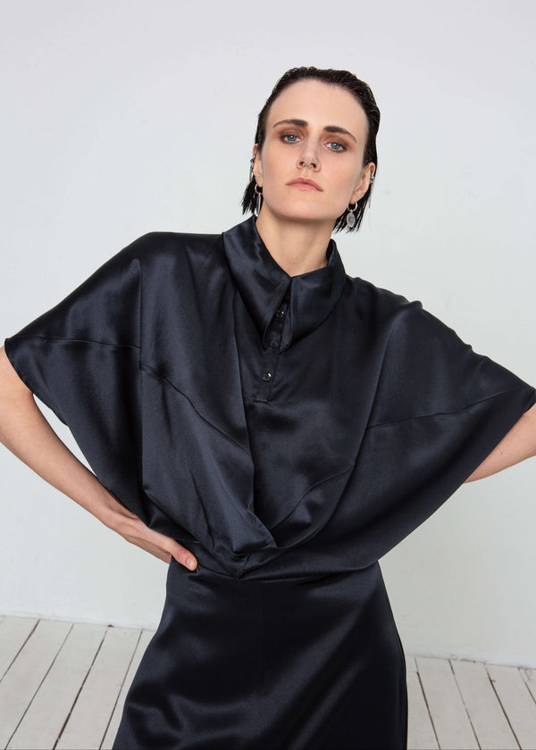 INTERNATIONAL CITIZEN.  Style: Prism Top, using sacred geometry of a 3-dimensional prism falling over the body in a soft cowl drape with an origami folded collar at the front placket. Made of Organic Silk, Obsidian Black. Spiritually Infused, Sustainable Luxury Fashion in Berlin. Front photo.