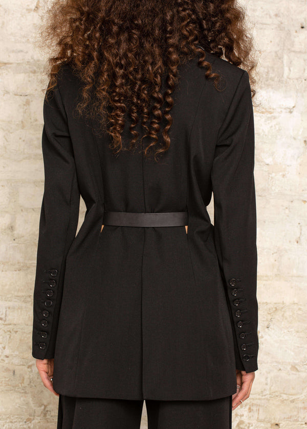 INTERNATIONAL CITIZEN.  Style: The Heart Opener Jacket features slim sleeves cut on the bias, a clean fitted shoulder and straight body, creating a cool silhouette that can be belted for an hourglass shape. Close up back photo. Made of Italian Wool, certified (RWS) Responsible Wool Standard, Obsidian Black. Spiritually Infused, Sustainable Luxury Fashion in Berlin.
