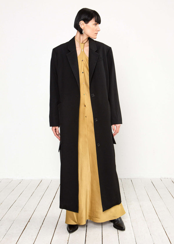 INTERNATIONAL CITIZEN.  Style: Duster Coat. A unisex coat that features traditional men's tailoring construction details. Front view. The coat is made of Italian RWS Wool in Obsidian Black. Spiritually Infused, Sustainable Luxury Fashion in Berlin.