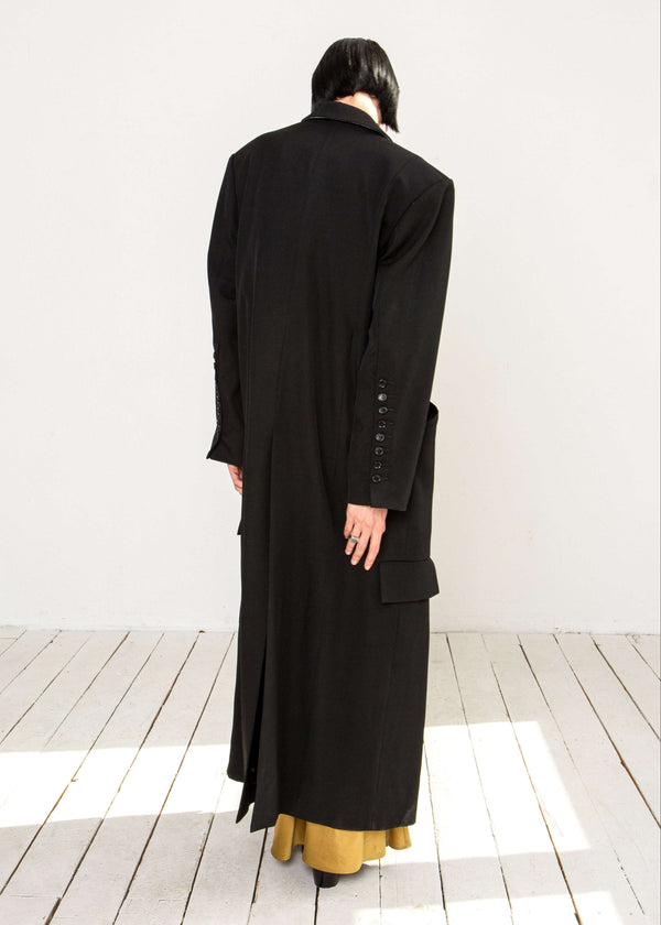 INTERNATIONAL CITIZEN.  Style: Duster Coat. A unisex coat that features traditional men's tailoring construction details. Back view. The coat is made of Italian RWS Wool in Obsidian Black. Spiritually Infused, Sustainable Luxury Fashion in Berlin.
