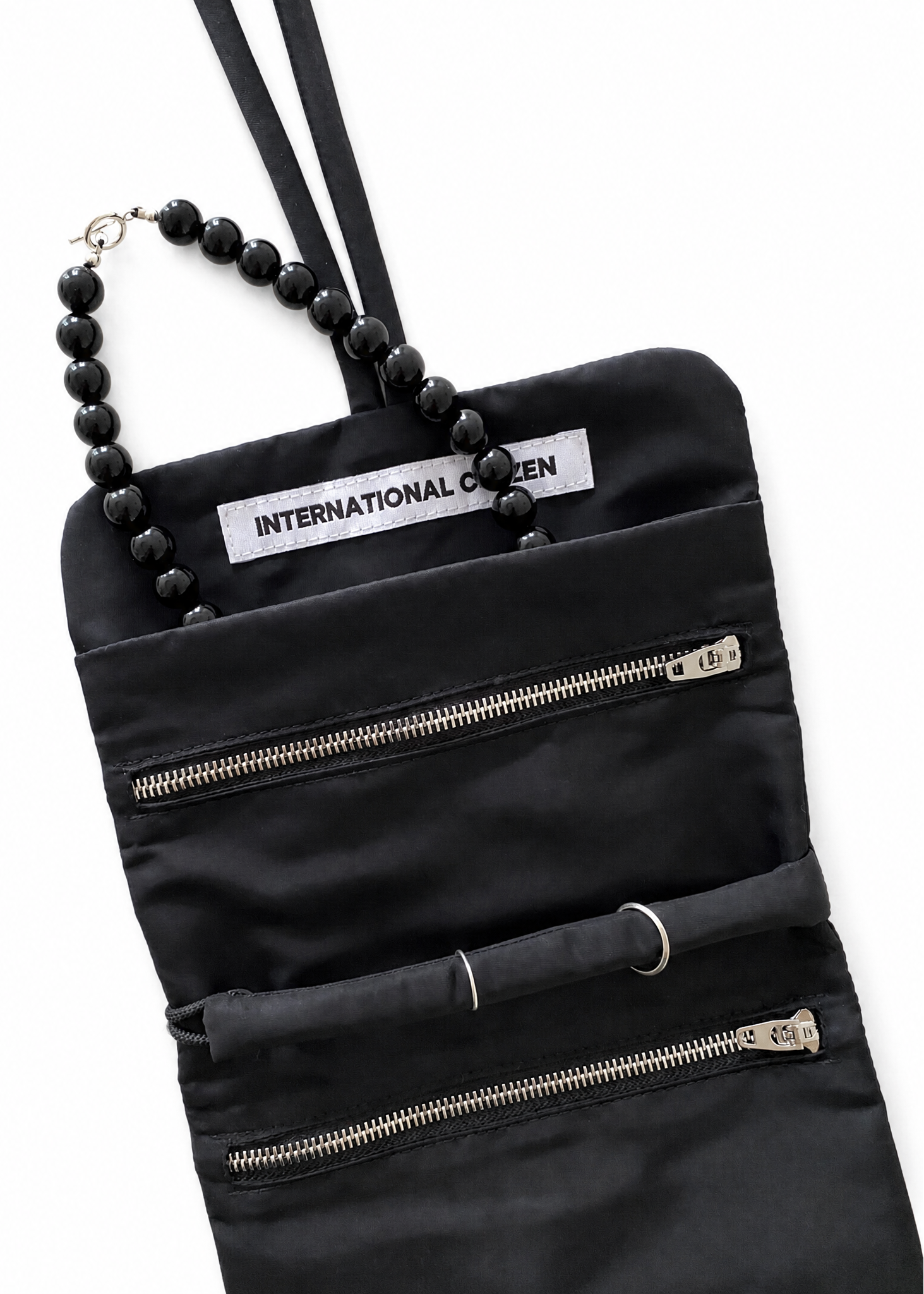 INTERNATIONAL CITIZEN: The Jewel Travel Bag is made of water repellent reNylon Gabardine. It features a zipper welt pocket to store you jewelry that folds and ties for closure. Shown with a necklace in the pocket.