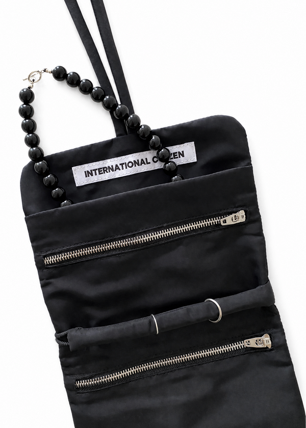 INTERNATIONAL CITIZEN: The Jewel Travel Bag is made of water repellent reNylon Gabardine. It features a zipper welt pocket to store you jewelry that folds and ties for closure. Shown with a necklace in the pocket.