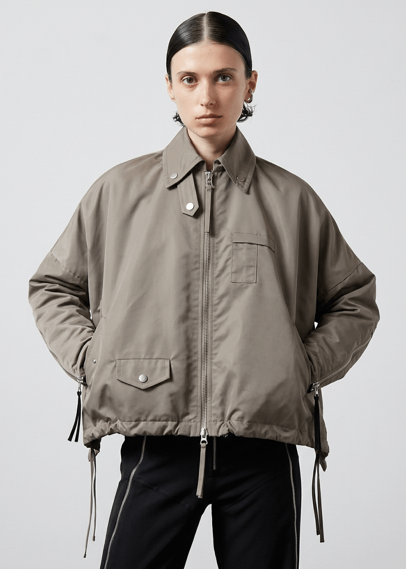 INTERNATIONAL CITIZEN.  Style: The Cube Coat, is a 3D cube tilted on its axes to create a boxy minimal front body. It has zipper closures, and a drawcord at the front hemline and a utility pen pocket on the chest. Unisex style. Made of Italian post-consumer recycled Nylon, Dune. Spiritually Infused, Sustainable Luxury Fashion in Berlin.