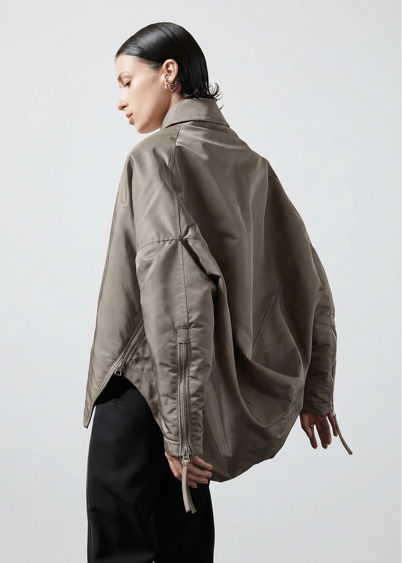INTERNATIONAL CITIZEN.  Style: The Cube Coat, is a 3D cube tilted on its axes to create a dramatic drape in the back body. It has zipper closures, and a drawcord at the front hemline. Unisex style. Made of Italian post-consumer recycled Nylon, Dune. Spiritually Infused, Sustainable Luxury Fashion in Berlin.