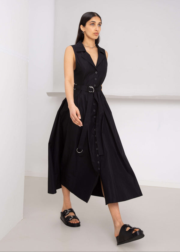 INTERNATIONAL CITIZEN.  Style: Button Dress. Walking front photo. A Button Dress with princess seams that open to box pleats below the hips. Detachable belt with silver ring details for closure. The dress is made of Italian organic Cotton in Obsidian Black. Spiritually Infused, Sustainable Luxury Fashion in Berlin.