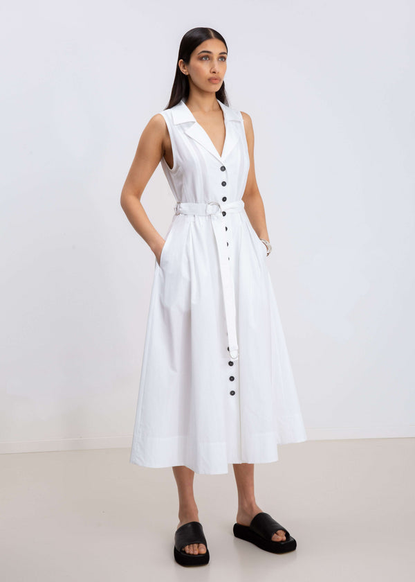 INTERNATIONAL CITIZEN.  Style: Button Dress. Side front view. A Button Dress with princess seams that open to box pleats below the hips. Detachable belt with silver ring details for closure. The dress is made of Italian organic Cotton in White Quartz. Spiritually Infused, Sustainable Luxury Fashion in Berlin.